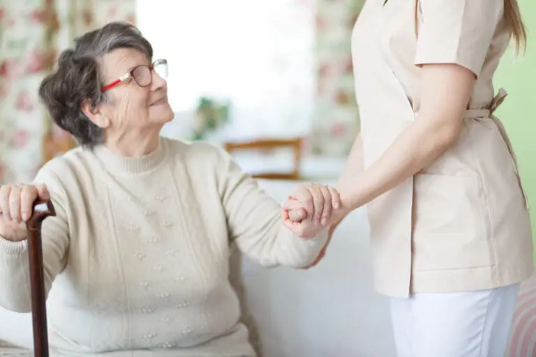 Senior Woman Holding Hands with Nurse in Home