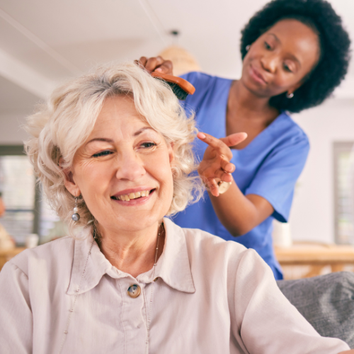 caregiver brushing elderly woman's hair