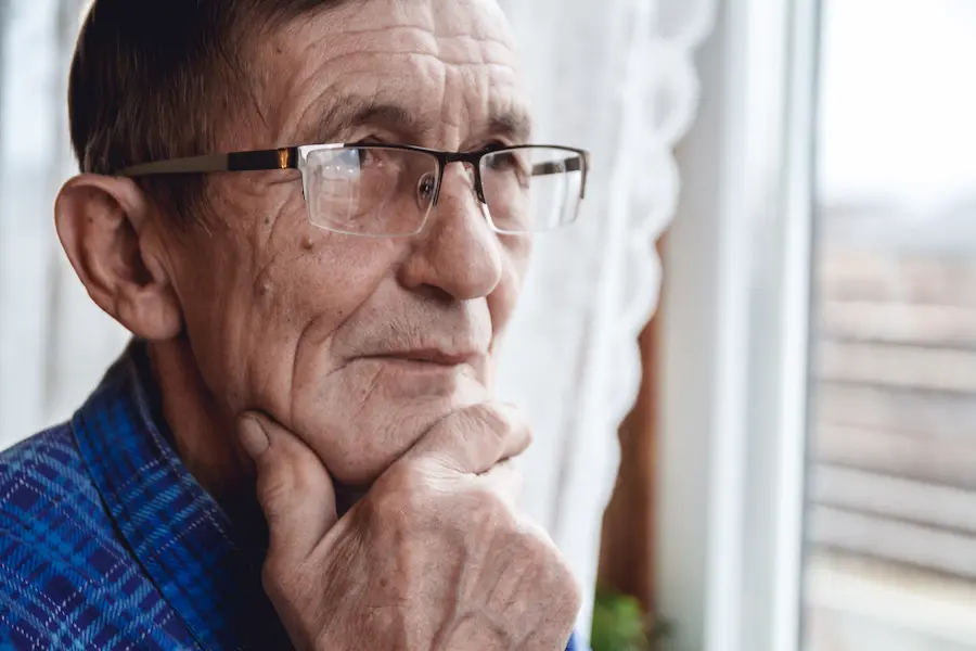 senior standing at the window and thinking