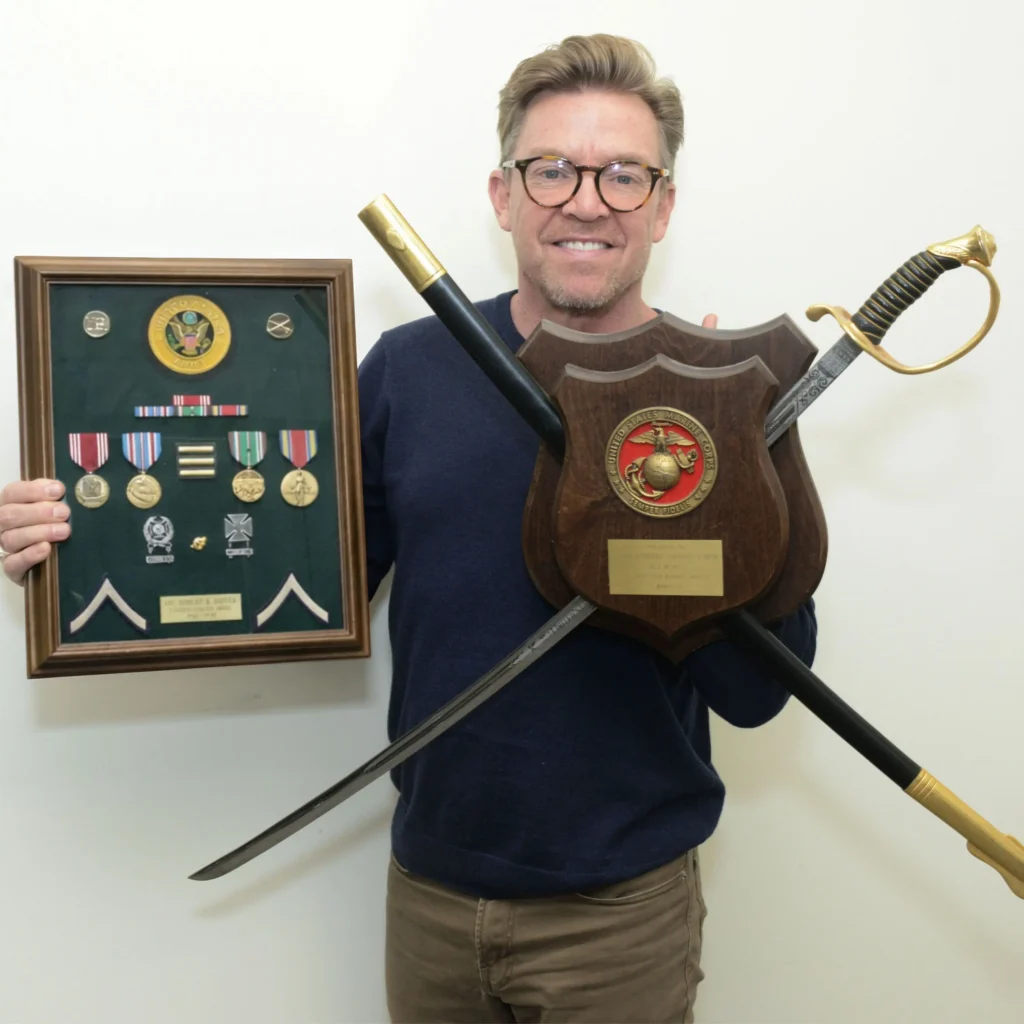 Chief Operating Officer Ernie Cote pictured holding Robert Foster's WWI medals and the M1859 NCO Sword used in the military wedding of his mother and step-father, Tommy Griffin.
