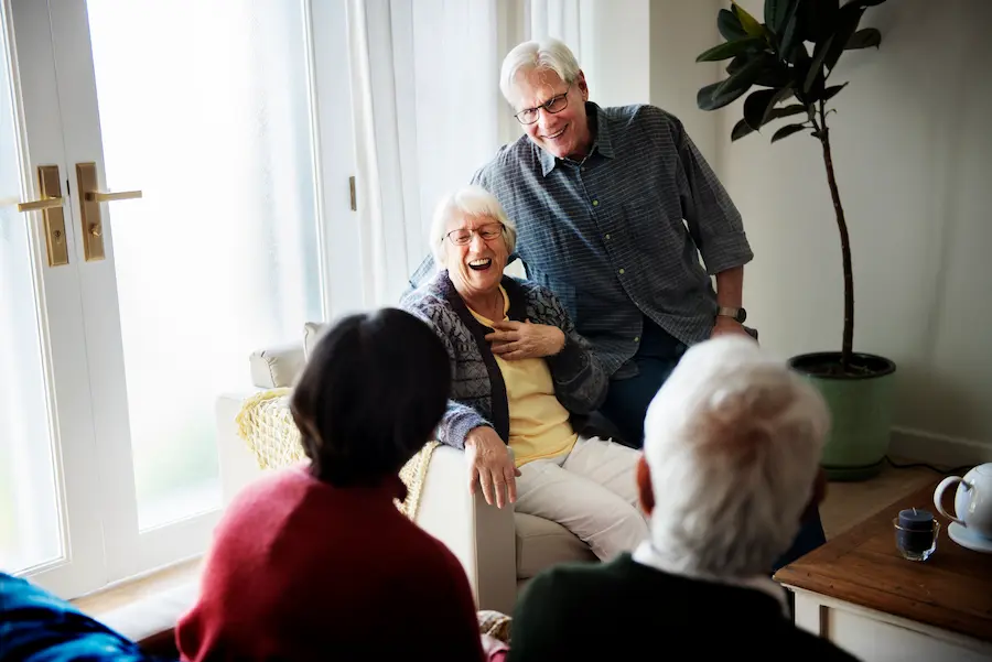 Laughing Senior Couple with Friends Indoors